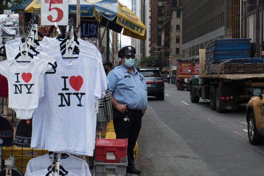 Manhattan, New York. October 01, 2020. A security guard wearing a mask next to an outside tourist stand selling t-shirts.