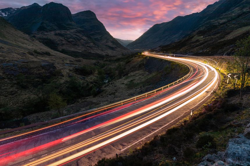 Car light trails on winding road through the highlands near Glencoe in Scotland at dusk - Travel and transport concepts in a scenic place with beautiful nature and views
