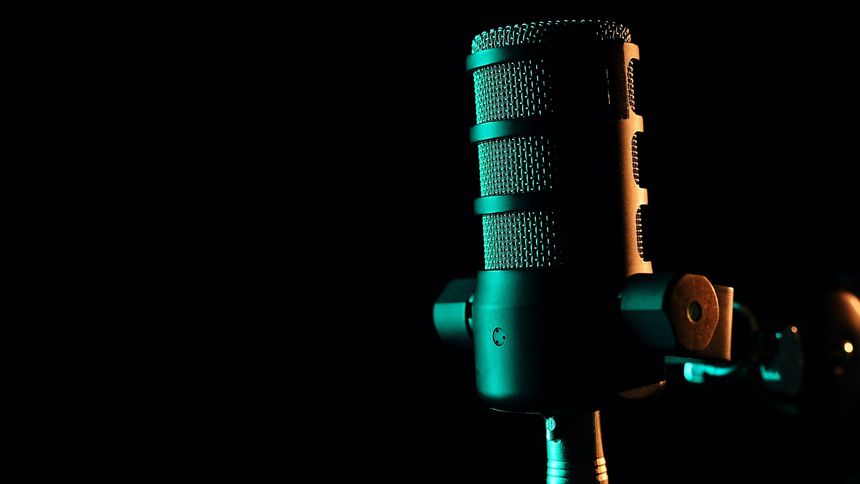 A professional studio microphone illuminated by atmospheric green lighting against a dark background. A sleek and modern setup for podcasting, broadcasting, and voice recording.