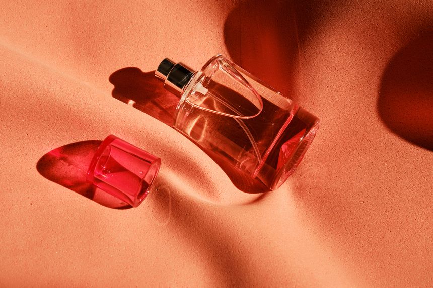 A pink perfume bottle on a soft reddish background. High quality photo.