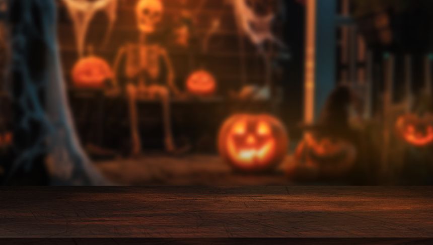 Dark wooden tabletop with blurred Halloween porch decor in the background. Ideal for seasonal mockups or festive design.