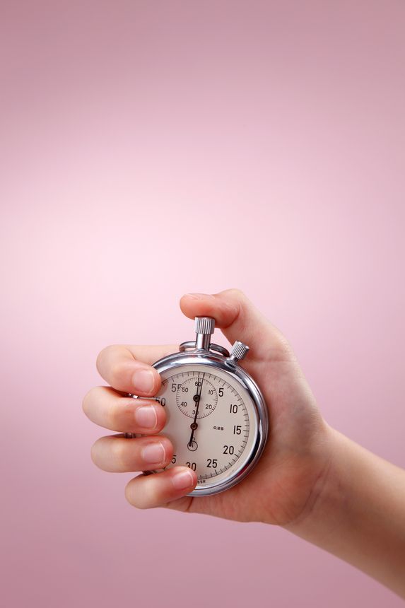 Cropped Hand Holding Stopwatch Against Pink Background