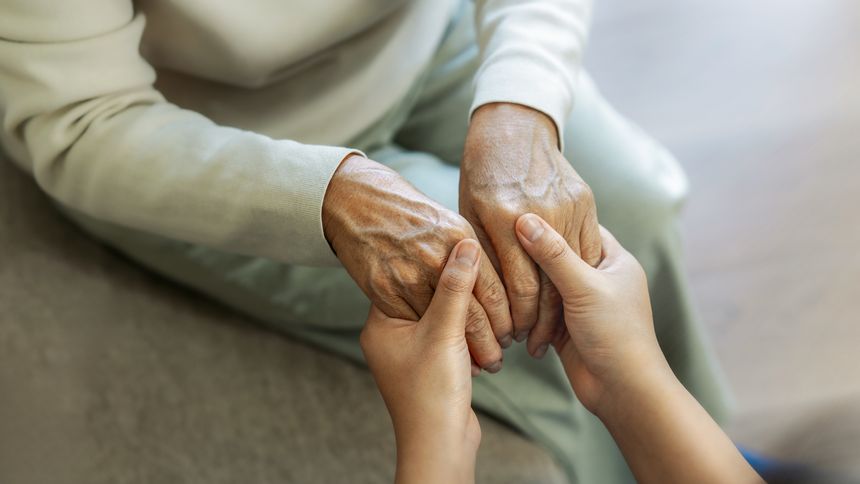A female nurse caregiver holds hands to encourage and comfort an elderly woman. For care and trust in nursing homes for people of retirement age Caregiver helping elderly woman provides medical advice