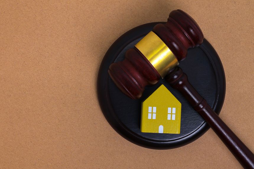 Judge’s gavel placed beside a miniature house, symbolizing property law, legal authority, and real estate regulation with copy space