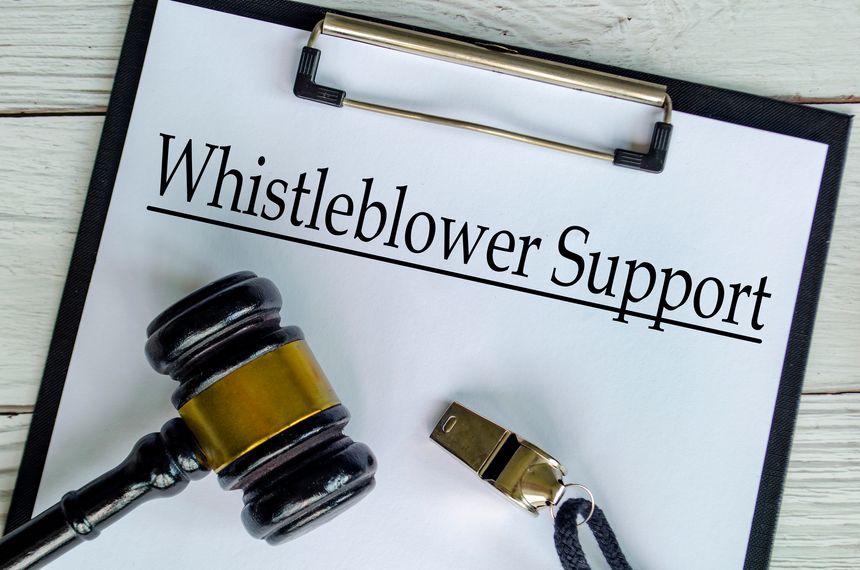 Top view of Whistleblower Support text on white paper clipboard with gavel and a whistle. Whistleblower protection and compliance concept.