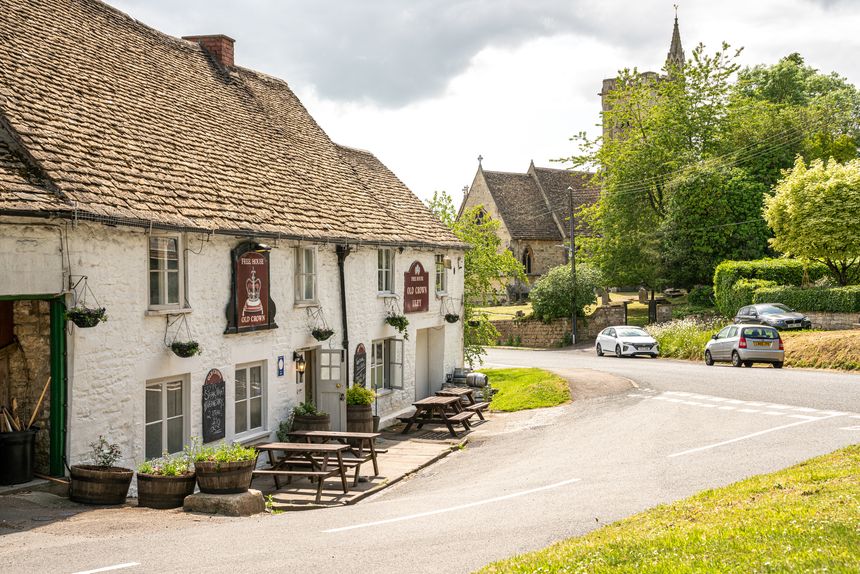 Uley, United Kingdom - June 3 2019: The Cotswold village of Uley with the Old Crown country pub and The Church of Saint Giles, United Kingdom