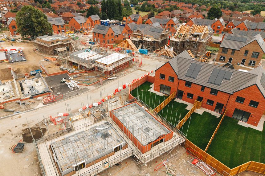 Construction workers are busy building new homes in a suburban neighborhood. Various houses are taking shape, while others are in different stages of completion.