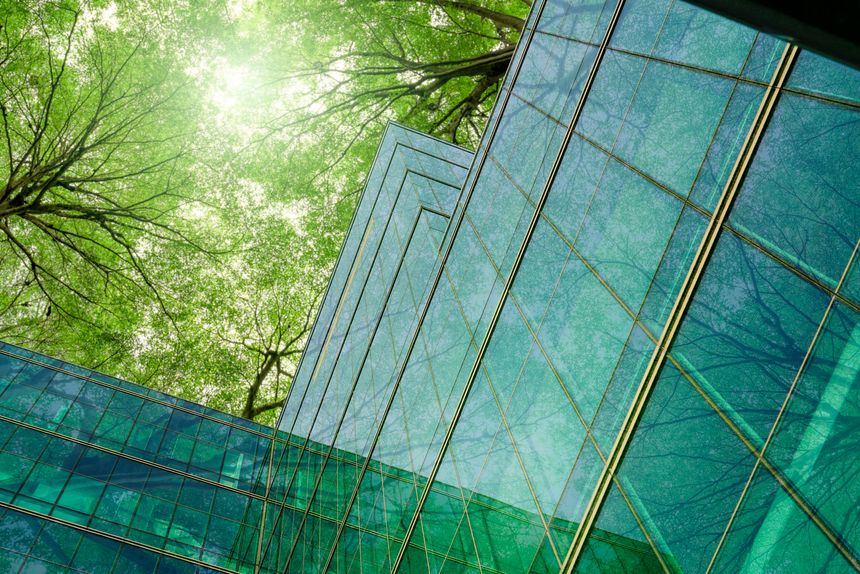 Eco-friendly building in modern city. Sustainable glass office building with trees for reducing carbon dioxide. Office building with green environment. Corporate building reduce CO2. Net zero emission
