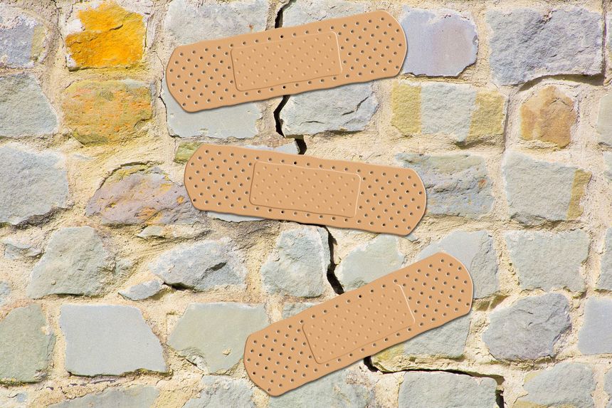 Old cracked and damaged stone wall cause due to subsidence of foundations structural failures - concept with adhesive bandage