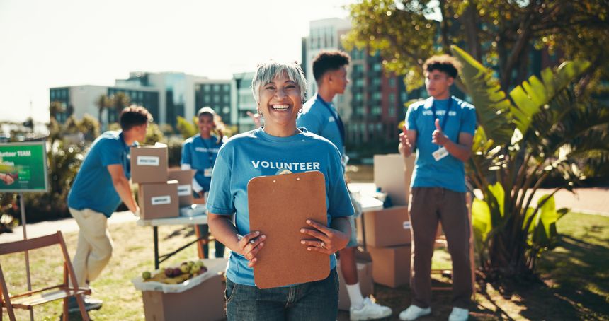 Portrait, volunteers and mature woman with clipboard, charity and inventory for donations, group or ngo. Outdoor, joy and coordinator with checklist for info, community service or boxes for nonprofit