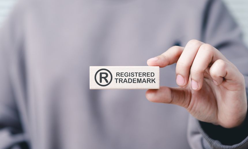 Registered trademark, intellectual property concept. A person holds wooden block the registered trademark symbol and text, representing intellectual property, copyright, patent, and brand protection.