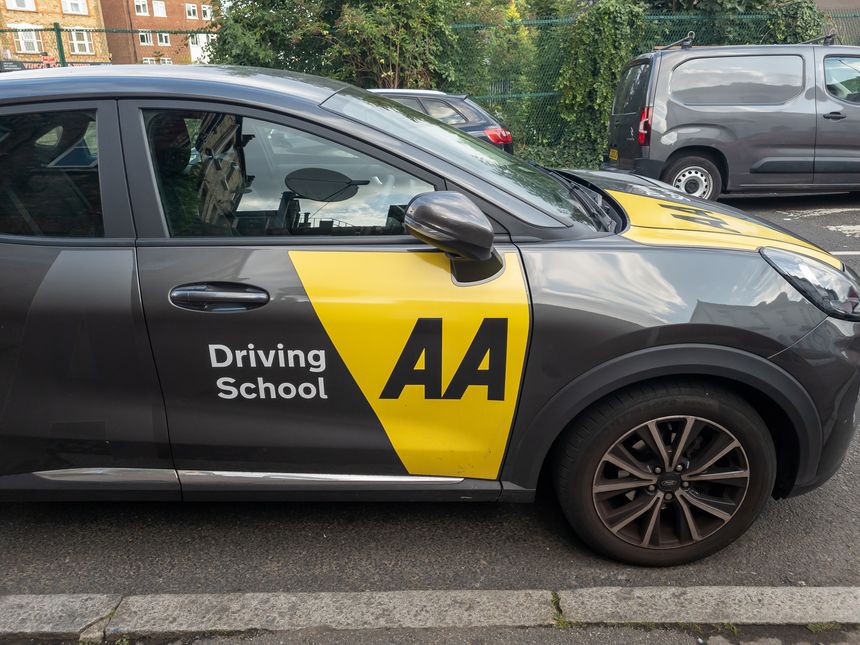 London. UK- July 31. 2025. Side view of an AA Driving School vehicle parked on a street.