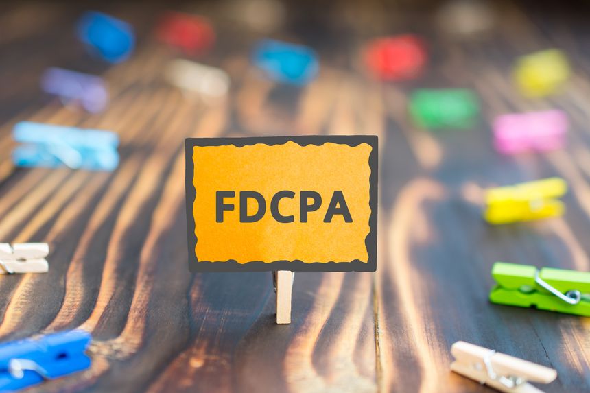sign board with an inscription FDCPA, Fair Debt Collection Practices Act, on a wooden background and colored clothespins
