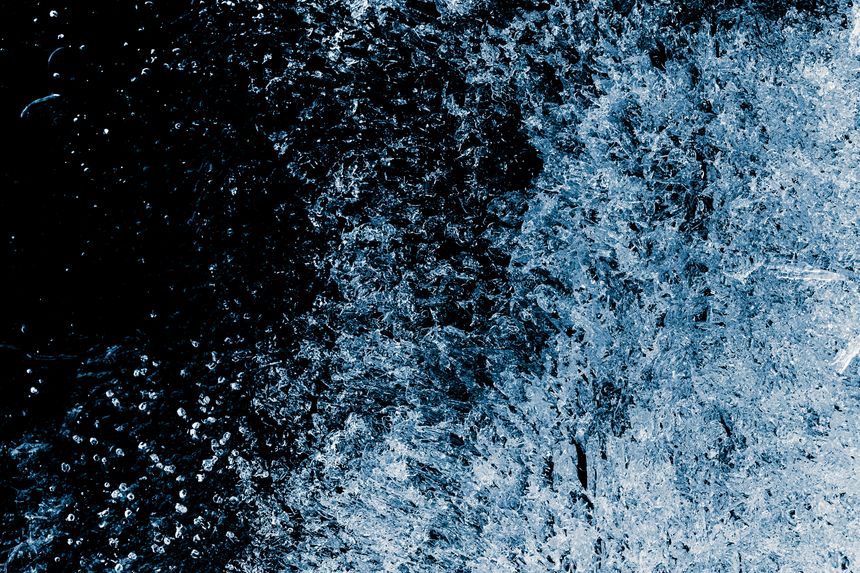 Ice texture background. The textured rough crystals of a cold frosty surface of the ice block on a black background.