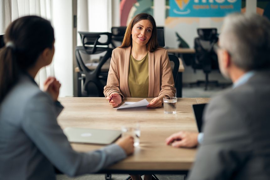 A structured job interview with participants exchanging insights, taking place in a modern, open office environment.