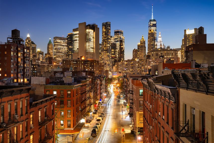 Chinatown and Lower Manhattan in New York City in evening. Illuminated skyscrapers, streets, and skyline at dusk