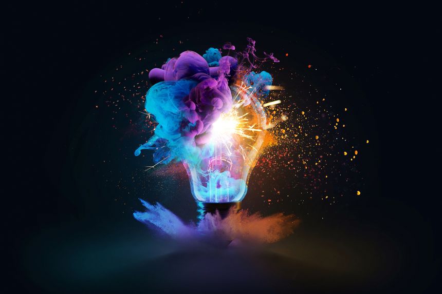 Creative light bulb explodes with colorful dry paint, sparks and splashes on a black background, concept. Think differently creative idea concept. Motion Color drop in water, Ink swirling