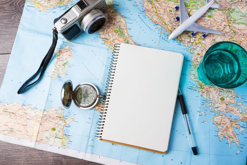 travel tourism agency table mockup tools compass, glass of water note pad, pen and toy airplane and touristic map on wooden table. Empty space you can place your text or information.