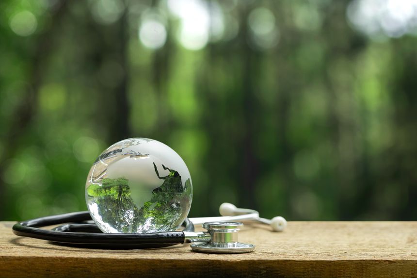 A glass globe with a stethoscope on a wooden table symbolizes world health, sustainability, and environmental care. Concept for saving the planet, eco medicine, global healthcare, and green living.