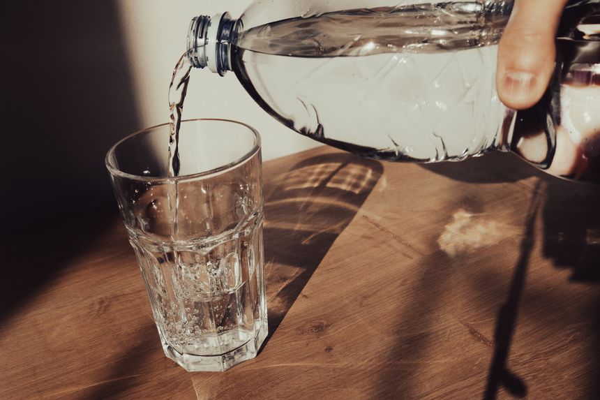 Man pouring mineral water from plastic bottle in glass. Male hand pour water in glass from bottle