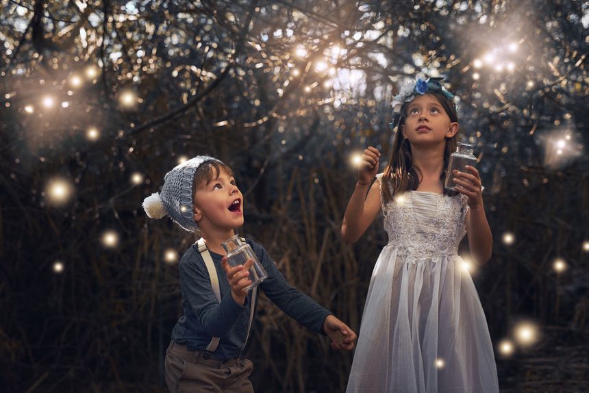 Shot of two little siblings catching fireflies in jars outside
