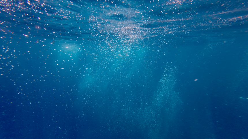 Abstract underwater scene with sunlight rays and floating bubbles, creating a clean marine background with motion and depth.