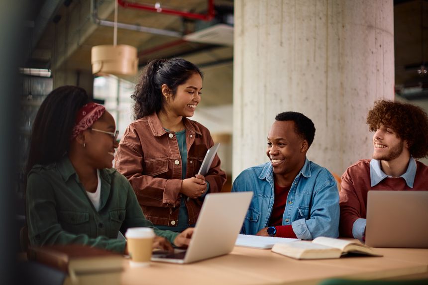 Multiracial group of happy college friends cooperating while studying at campus.