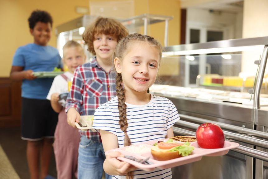 Little girl with tray of tasty food in school canteen, selective focus