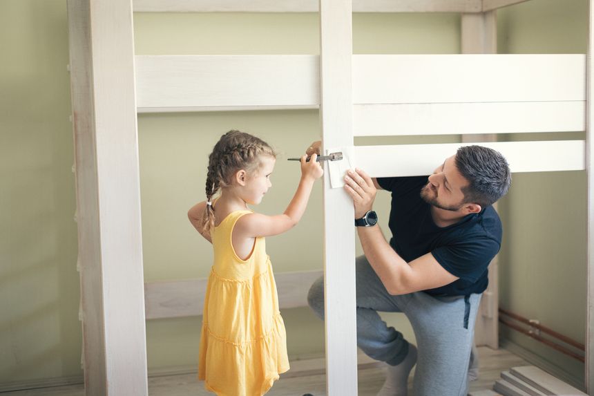 Young man with his daughter assembling furniture at home. Shallow DOF. Developed from RAW; retouched with special care and attention; Small amount of grain added for best final impression.16 bit Adobe RGB color profile.