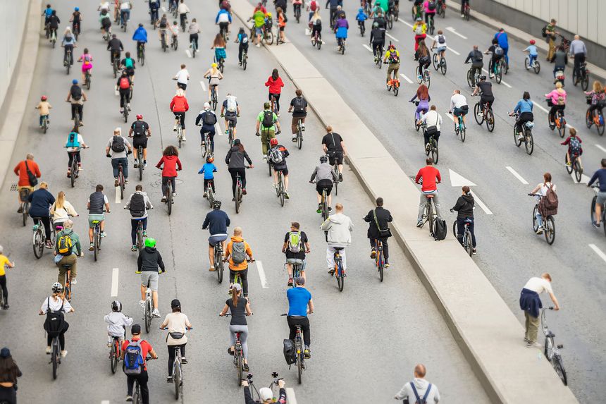 Large crowd of cyclists riding on closed city highway during public bike event. Image symbolizes unity, eco transport, active sport lifestyle in urban environment
