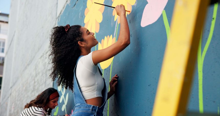 People, wall painting and women with volunteering, smile and cooperation for community project. Activist, artist and friends with creativity, art supplies and social responsibility with design