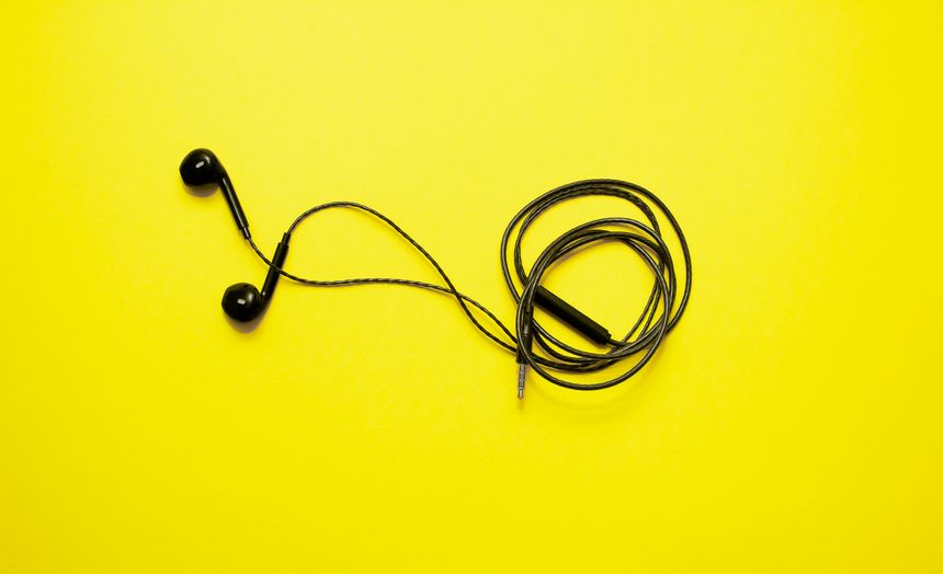 Black wired headphones isolated on yellow background. Modern gadgets for communication