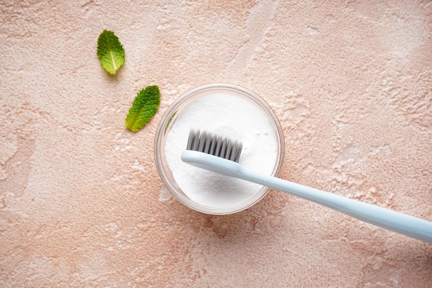 Toothbrush and tooth powder on a beige background with mint leaves, flat lay.