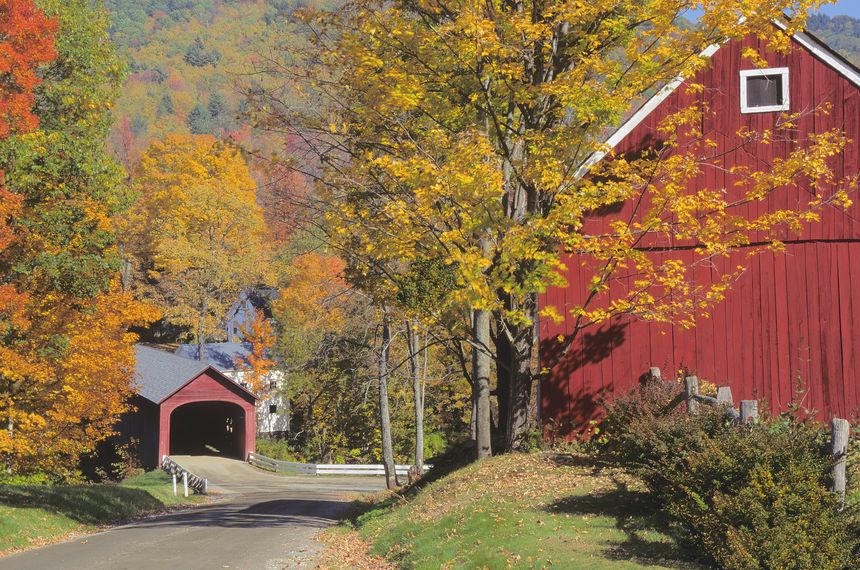 Autumn scene in the small picturesque village of Guilford Vermont with colorful fall foliage, red barn, and old covered bridge spanning the Green River.