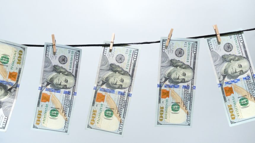 A symbolic image of money laundering, showcasing several one hundred dollar bills on a clothesline. This represents financial crime and the cleaning of dirty money for finance articles.