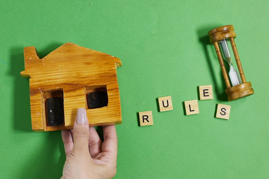 Wooden House Model and hand forming Rules text with Colorful Letters on Bright Green Background