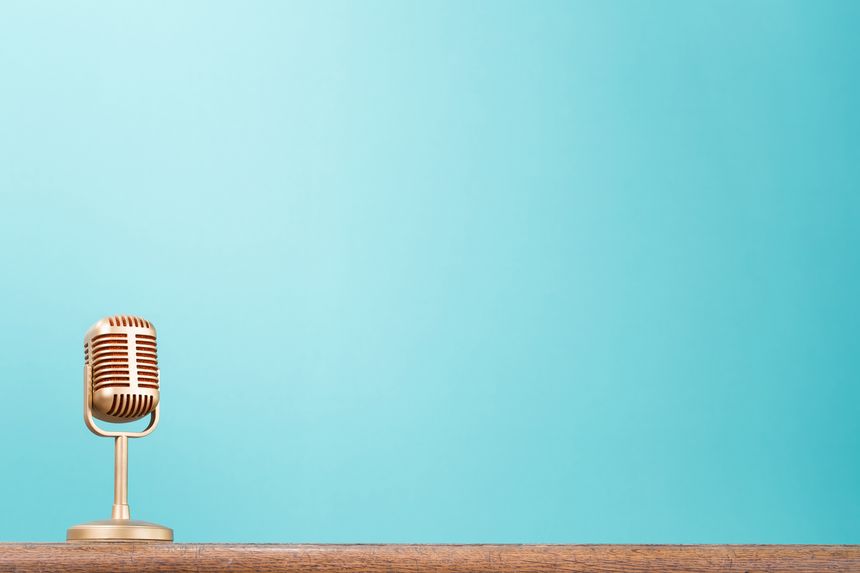 Retro gold microphone standing on wooden table front aquamarine wall background. Vintage style filtered photo