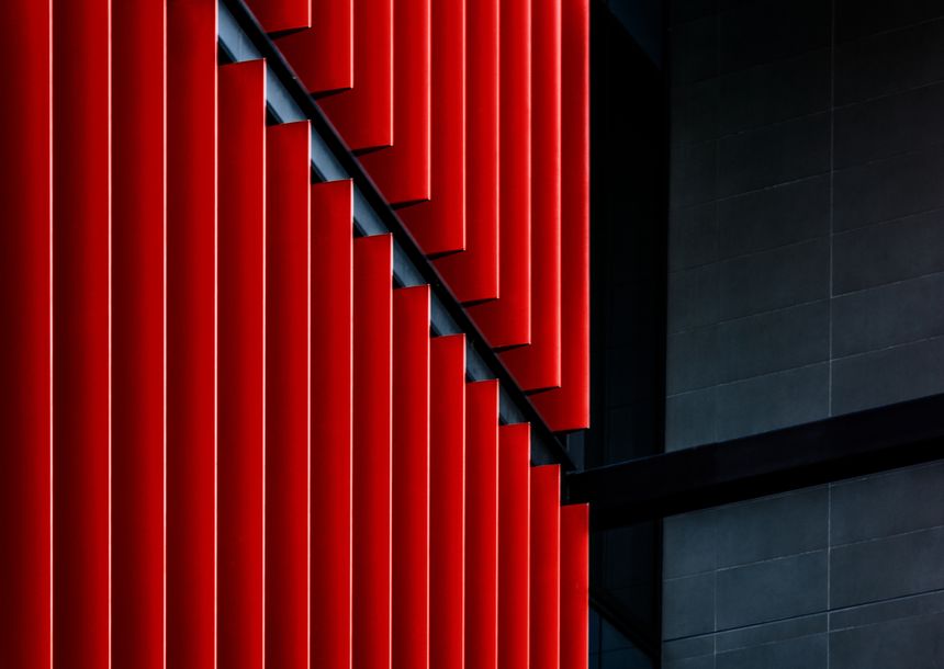 Abstract image of building facade with strong red vertical lines and black panels