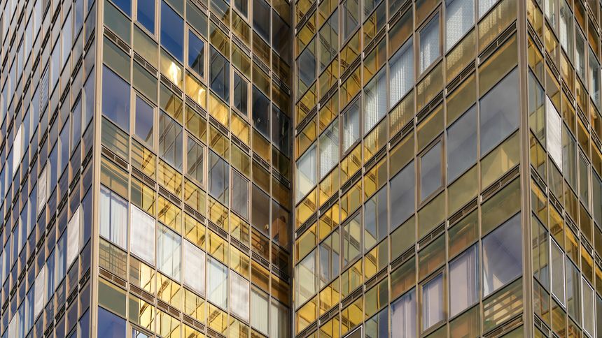 Modern building facade with golden reflective glass windows and geometric structure. Contemporary architecture. Real Photo.