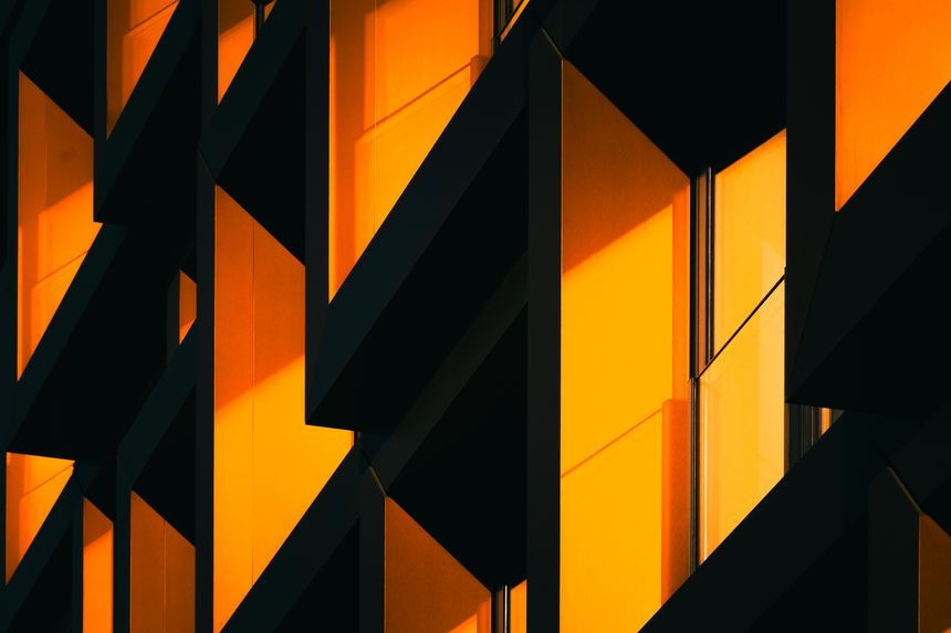 Close-up of modern architectural detail with interlocking orange metal frames in dramatic shadow, modern architecture concept