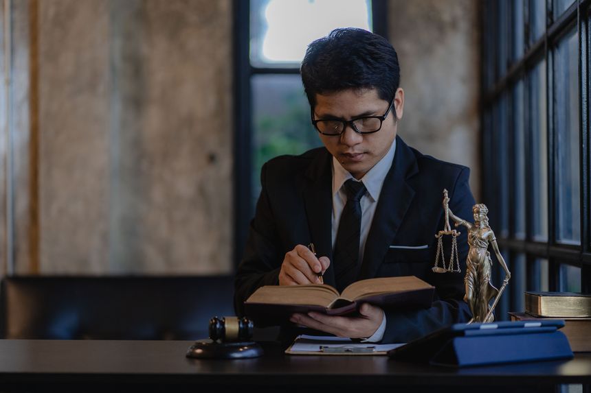 Asian male lawyer lawyer office working with hammer and scales god of justice and laptop with smartphone contract documents online legal counseling concept
