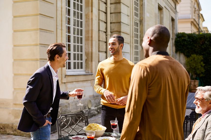 Shot of a group of men talking together while enjoying themselves outside at a garden party
