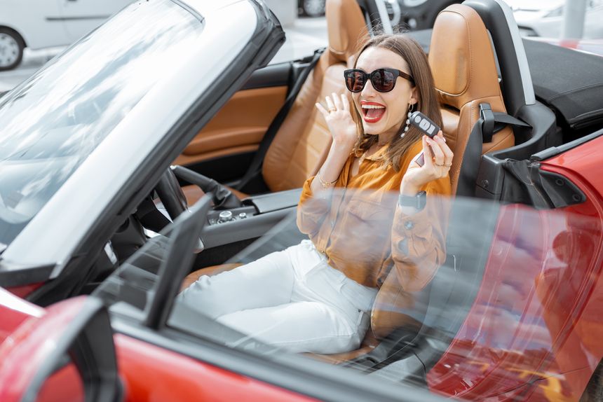 Portrait of cheerful woman feeling happy while sitting in the new sports car. Concept of a happy car buying or renting