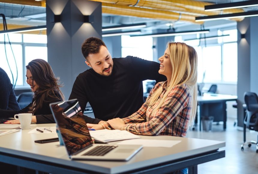 Man flirting with female colleague at the office meeting while she is laughing