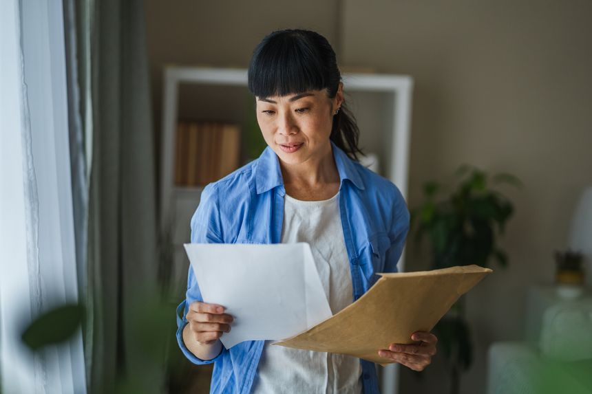 Japanese woman hold mail envelope letter with good news message at home