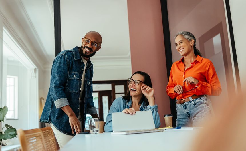 Group of creatives and freelancers enjoying collaboration in a modern, colorful office boardroom with a joyful team member.
