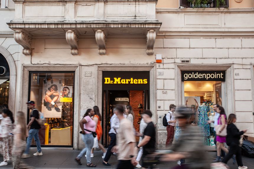Rome, Italy - June 15, 2024: This image captures the exterior of a Dr. Martens store in Rome, Italy. Shoppers and pedestrians hurry by, reflecting the brand's enduring popularity among diverse style enthusiasts. Dr. Martens, renowned for its iconic leather boots and rebellious heritage, showcases its footwear behind a prominent sign and storefront display. The dynamic street setting underscores the label's urban roots and global appeal, as well as Rome's status as a fashion hub blending classic architecture with contemporary retail culture.