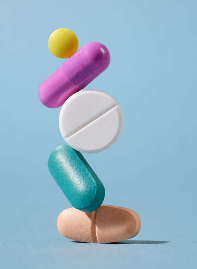 tower of various colorful pills on blue background