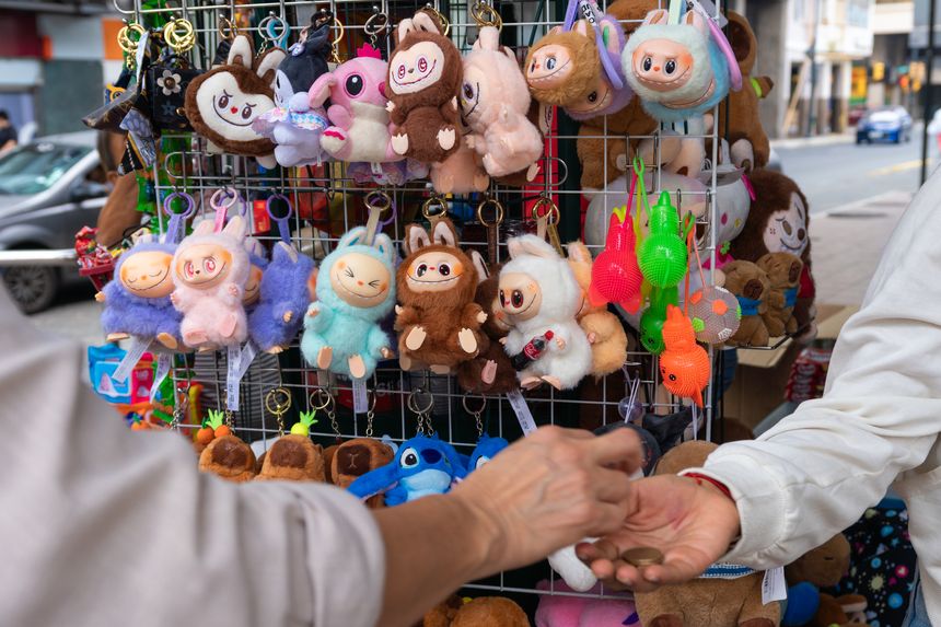 Guayaquil, Ecuador – July 27th, 2025: Informal sales stand with a variety of plush keychains and a coin payment transaction. Labubu