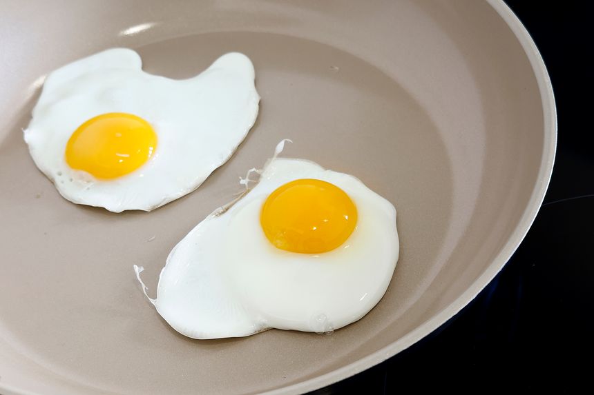 Fresh eggs being fried on ceramic pan UK